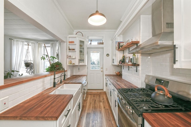 kitchen with white cabinets, stainless steel gas range, wall chimney exhaust hood, and wooden counters