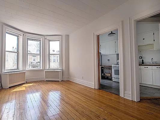 spare room featuring sink, radiator heating unit, and light hardwood / wood-style floors