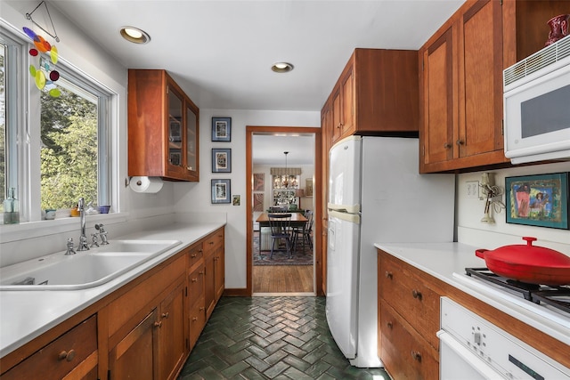 kitchen featuring white appliances, sink, and a notable chandelier