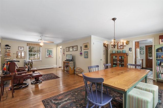 dining room featuring wood-type flooring, crown molding, ceiling fan with notable chandelier, and baseboard heating