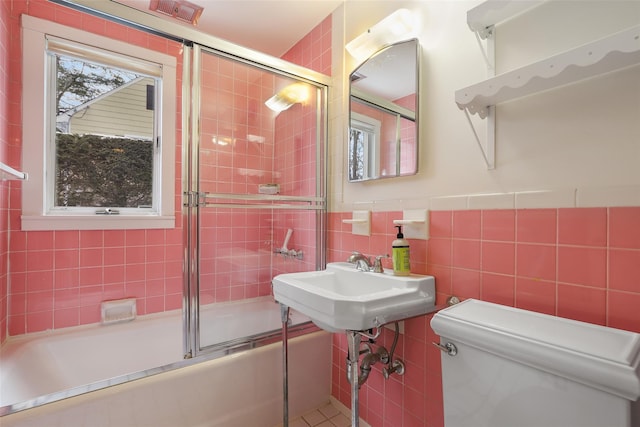 full bathroom with tile walls, sink, combined bath / shower with glass door, and toilet