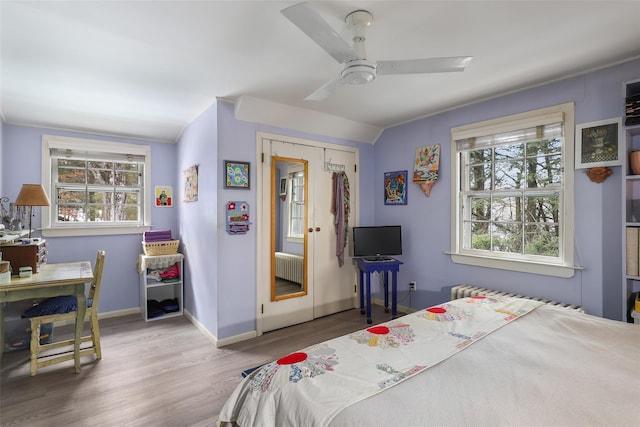 bedroom featuring wood-type flooring, radiator, ceiling fan, and a closet