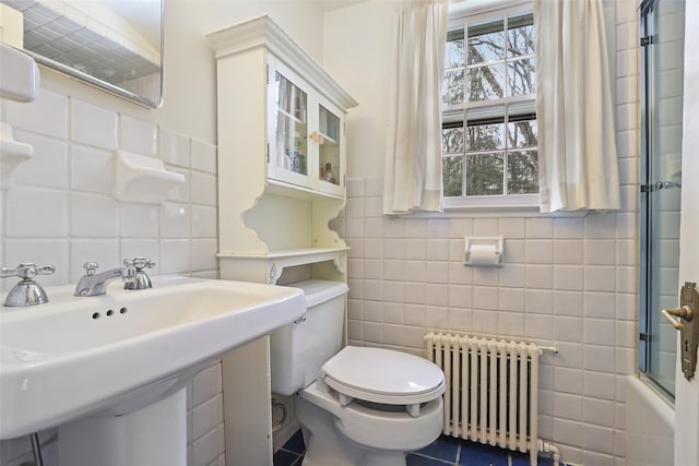 full bathroom with bath / shower combo with glass door, radiator, tile walls, and toilet