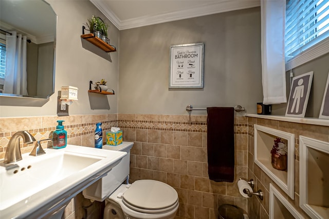 bathroom with toilet, crown molding, tile walls, and sink