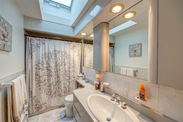 bathroom featuring toilet, vanity, a skylight, and a shower with curtain