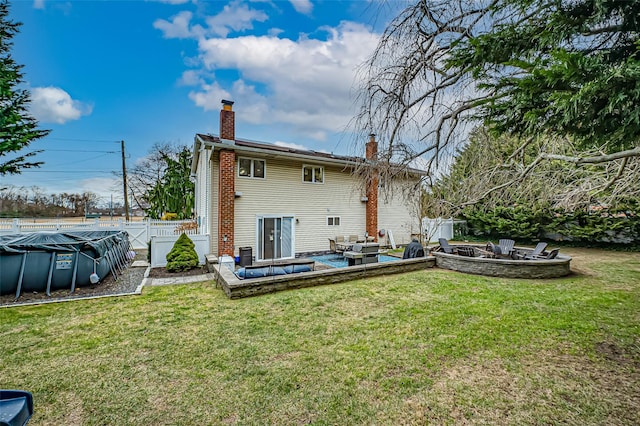 back of house featuring a patio area, a covered pool, an outdoor fire pit, a yard, and central AC unit