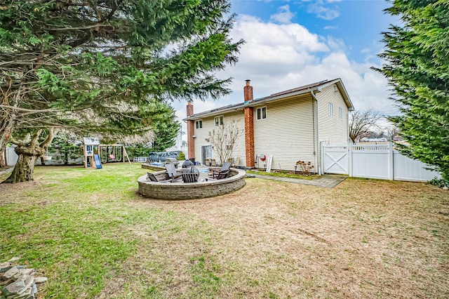 rear view of house with a playground, an outdoor fire pit, and a lawn