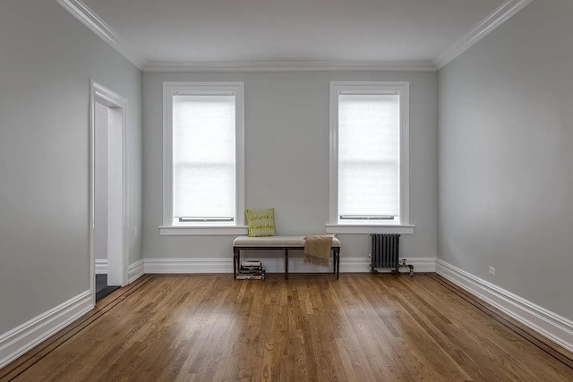 spare room featuring hardwood / wood-style floors, crown molding, and radiator heating unit