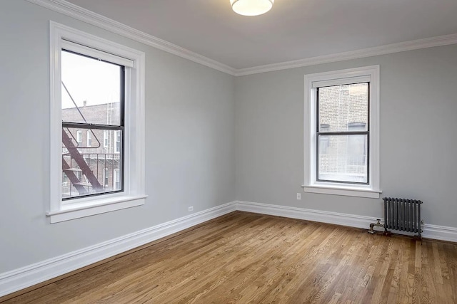 spare room featuring radiator, crown molding, plenty of natural light, and light wood-type flooring