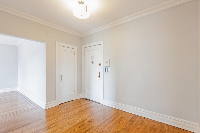 empty room with crown molding and light hardwood / wood-style flooring