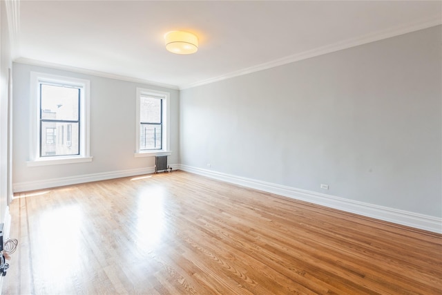 spare room featuring crown molding, radiator heating unit, and light hardwood / wood-style floors