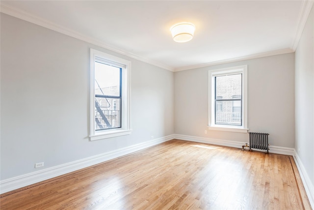 spare room with crown molding, radiator, and light hardwood / wood-style floors