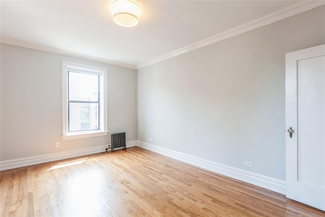 empty room featuring ornamental molding, radiator, and light hardwood / wood-style flooring