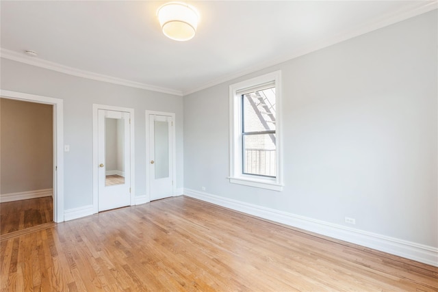 unfurnished bedroom featuring crown molding, light hardwood / wood-style flooring, and two closets