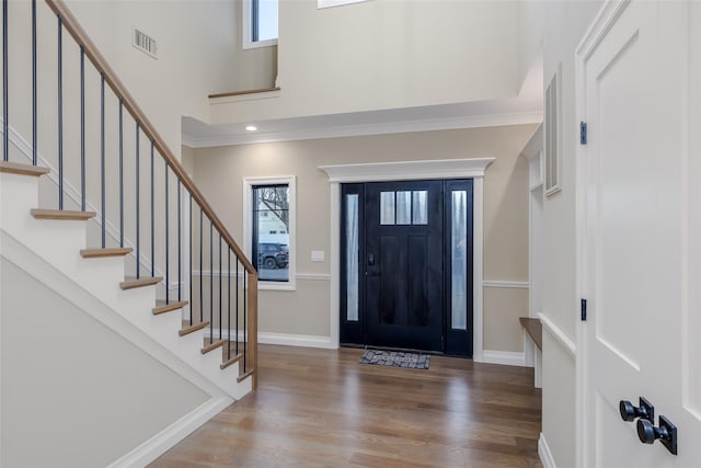 foyer with hardwood / wood-style flooring, a high ceiling, and crown molding