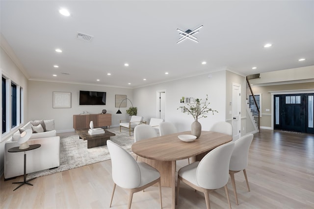 dining space with ornamental molding and light hardwood / wood-style flooring