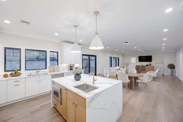 kitchen with sink, white cabinets, and a center island with sink