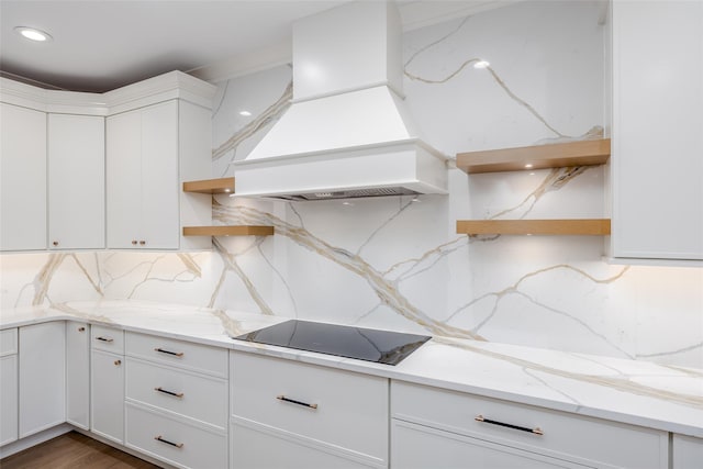 kitchen featuring white cabinetry, custom exhaust hood, light stone countertops, and black electric cooktop