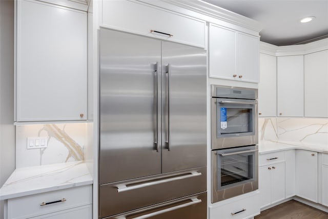 kitchen featuring white cabinets, stainless steel appliances, and light stone counters