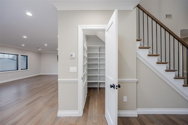 stairs with hardwood / wood-style flooring and ornamental molding