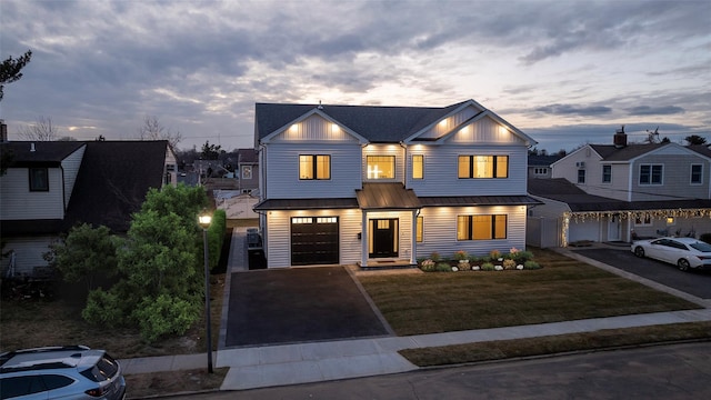 view of front of home with aphalt driveway, a front yard, metal roof, and an attached garage