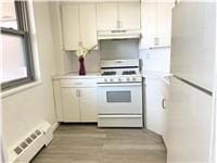 kitchen featuring white cabinets, white appliances, light hardwood / wood-style flooring, and a baseboard heating unit