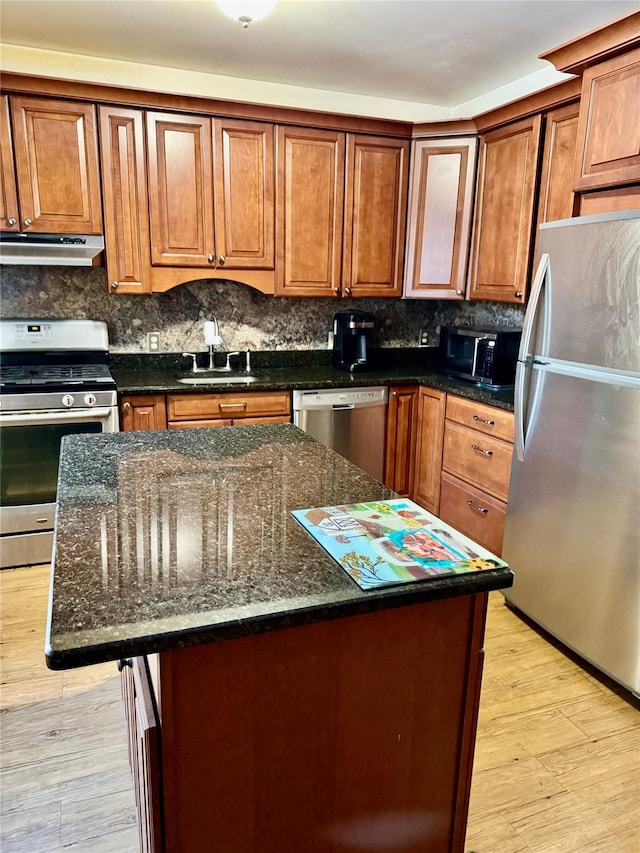 kitchen with appliances with stainless steel finishes, a center island, and dark stone counters