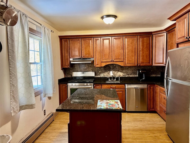 kitchen featuring sink, dark stone counters, a center island, baseboard heating, and stainless steel appliances