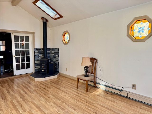 unfurnished room featuring a baseboard radiator, a wood stove, vaulted ceiling with skylight, and light hardwood / wood-style flooring