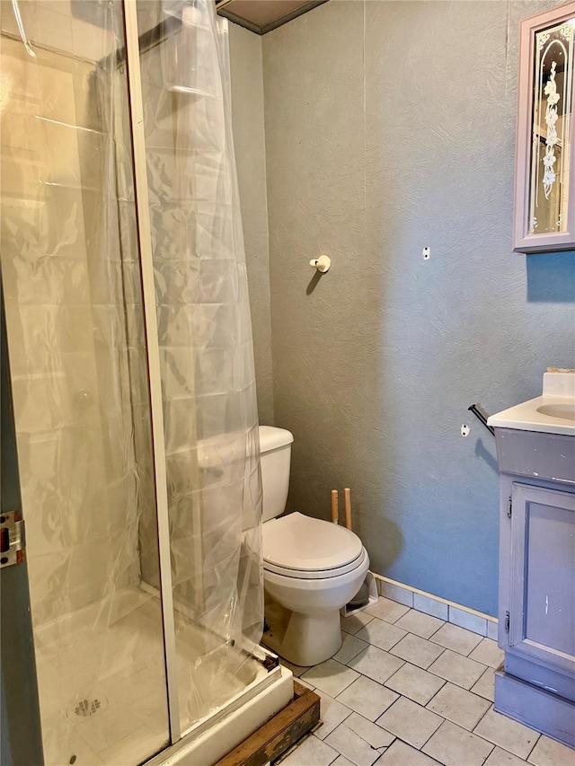 bathroom featuring walk in shower, vanity, tile patterned floors, and toilet