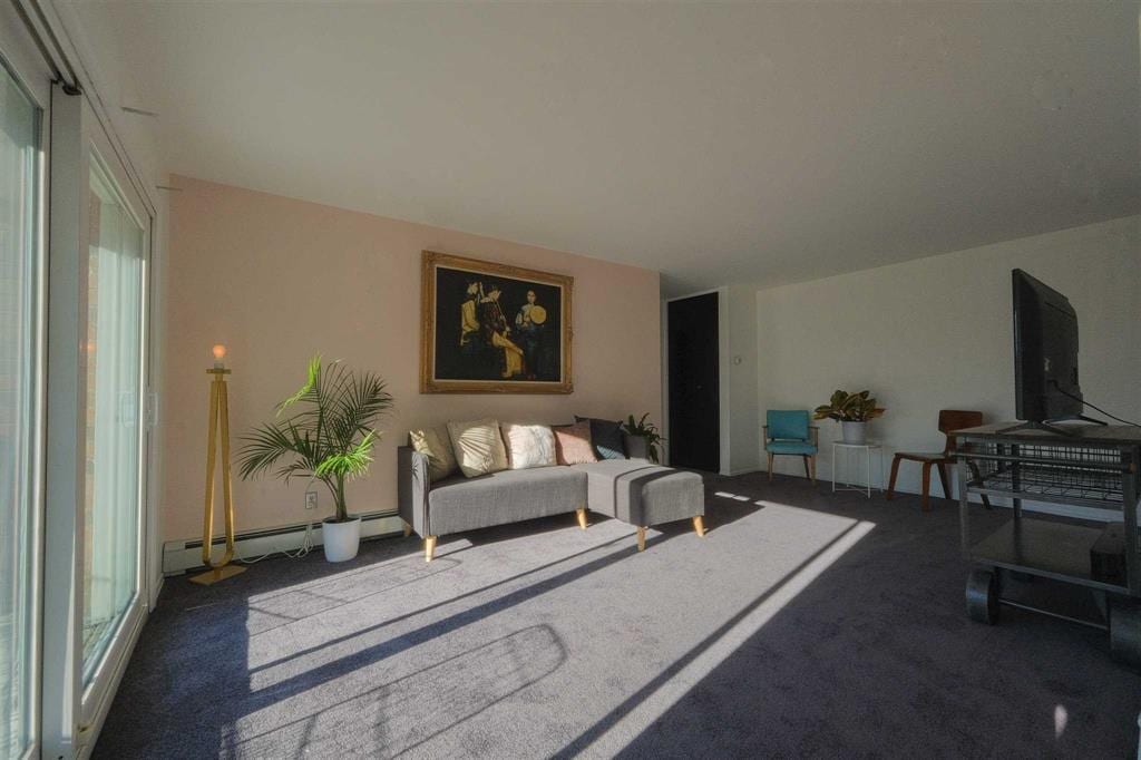 living room featuring baseboard heating, a wealth of natural light, and carpet