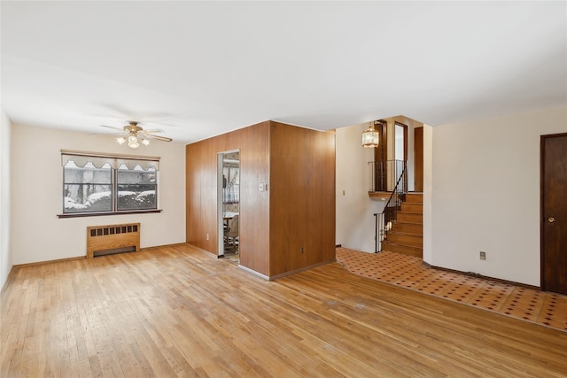 unfurnished living room with radiator heating unit, light wood-type flooring, and ceiling fan