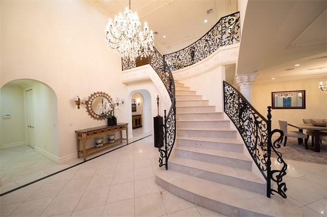 stairs with a high ceiling, tile patterned floors, and an inviting chandelier