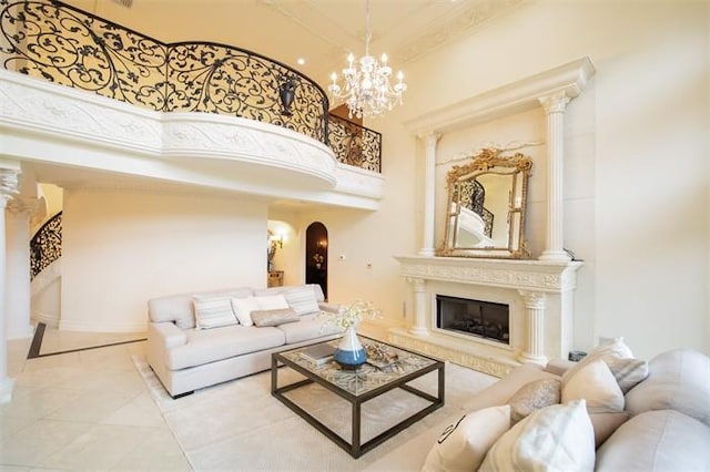 living room featuring crown molding, decorative columns, a chandelier, and a towering ceiling