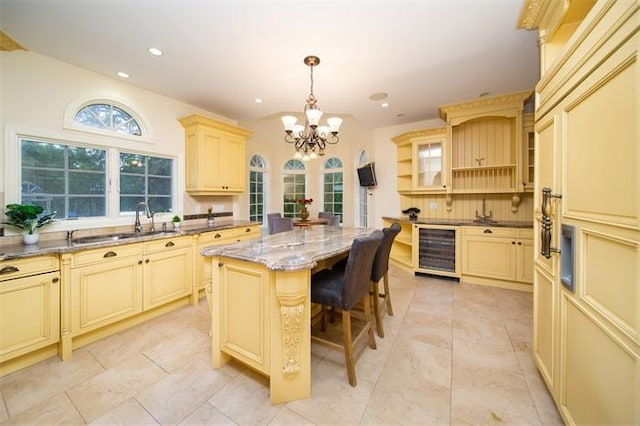 kitchen featuring a center island, light stone countertops, pendant lighting, a breakfast bar area, and beverage cooler