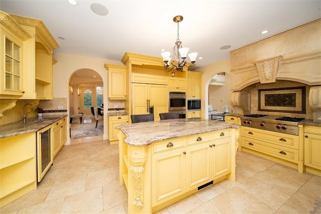 kitchen featuring a center island, an inviting chandelier, pendant lighting, stainless steel appliances, and beverage cooler