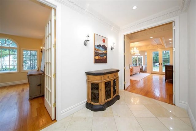 hallway featuring crown molding, plenty of natural light, light tile patterned floors, and french doors