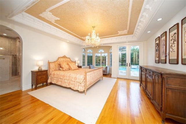 bedroom featuring crown molding, light hardwood / wood-style flooring, access to outside, french doors, and a raised ceiling