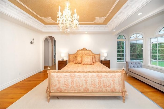 bedroom with ornamental molding, hardwood / wood-style floors, and a tray ceiling