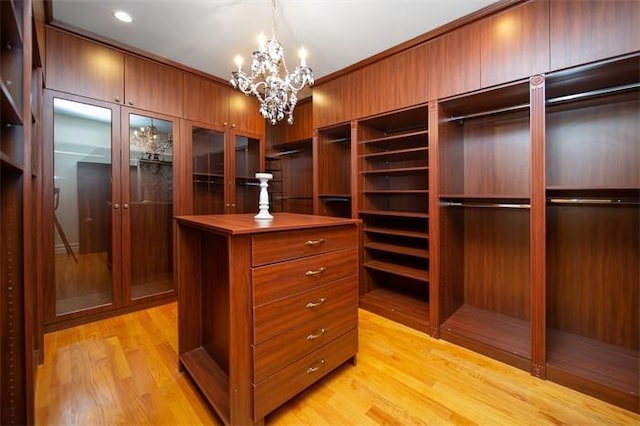 spacious closet featuring a notable chandelier and light hardwood / wood-style floors