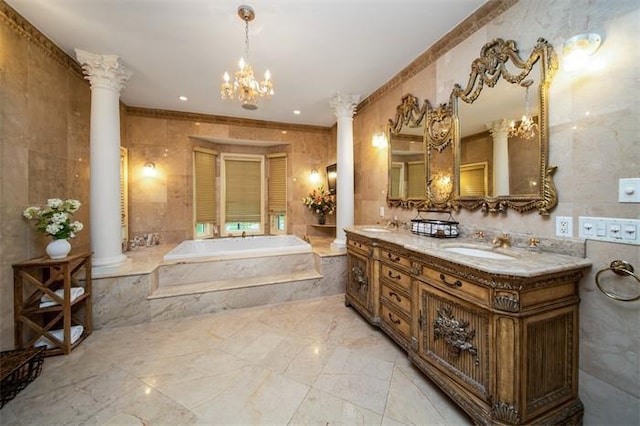 bathroom with a notable chandelier, ornate columns, tiled tub, tile walls, and vanity