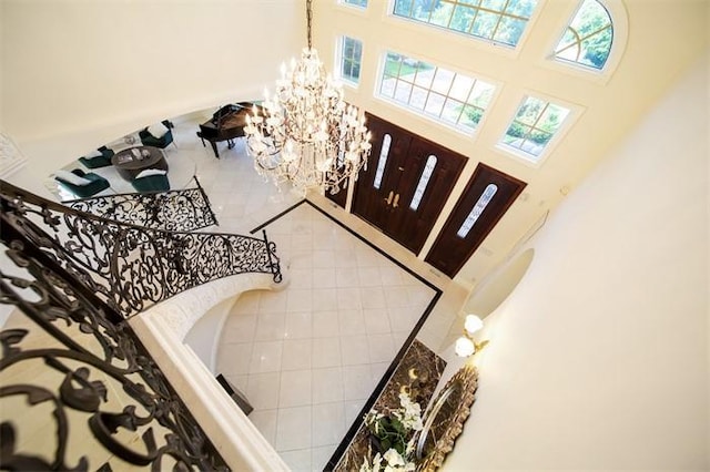 tiled foyer entrance with a notable chandelier, a wealth of natural light, and a high ceiling