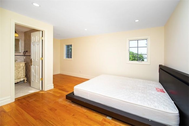 bedroom with hardwood / wood-style floors and ensuite bathroom