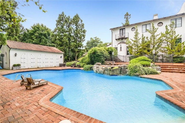 view of swimming pool with a patio, an outdoor structure, and pool water feature