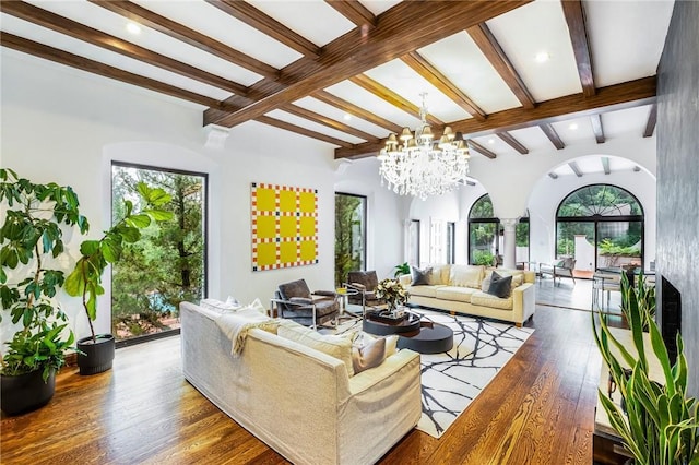 living room featuring hardwood / wood-style floors, decorative columns, a chandelier, and beamed ceiling