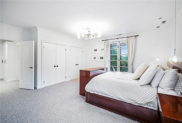 carpeted bedroom with a notable chandelier, ornamental molding, and multiple closets