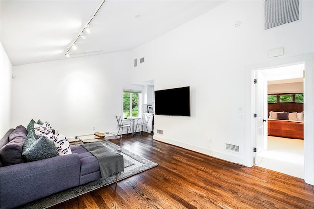 living room with hardwood / wood-style flooring, track lighting, and a high ceiling