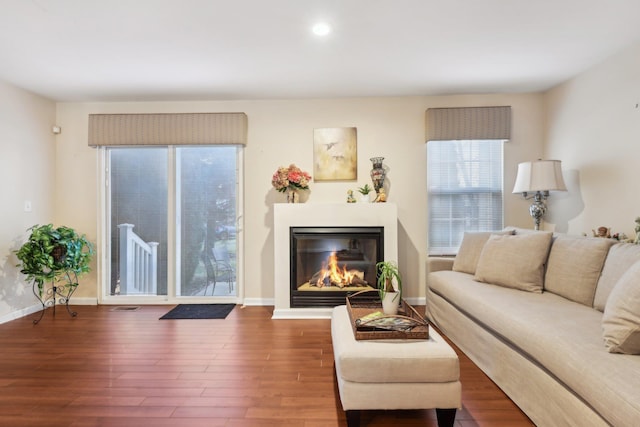 living area featuring wood finished floors, visible vents, baseboards, recessed lighting, and a glass covered fireplace