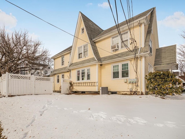 snow covered house featuring cooling unit and central air condition unit