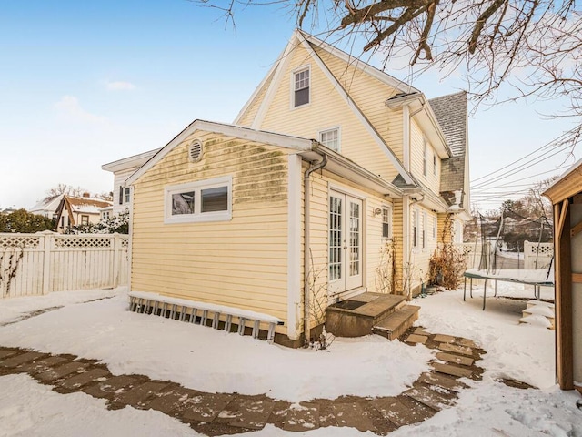 snow covered rear of property with a trampoline